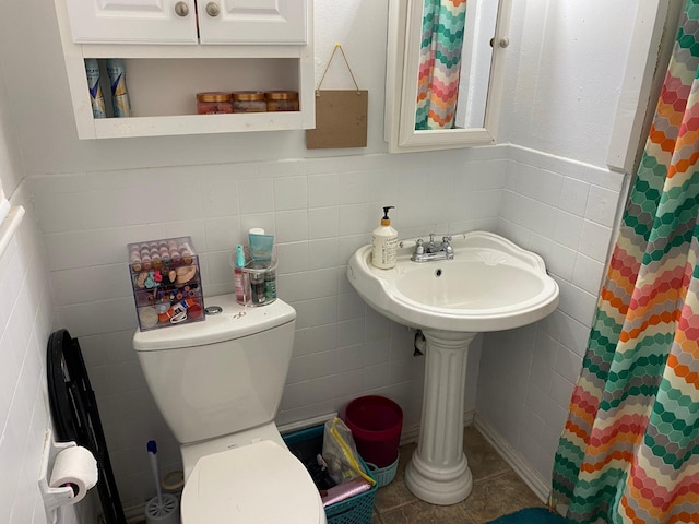 bathroom with a shower with curtain, toilet, tile patterned flooring, and tile walls