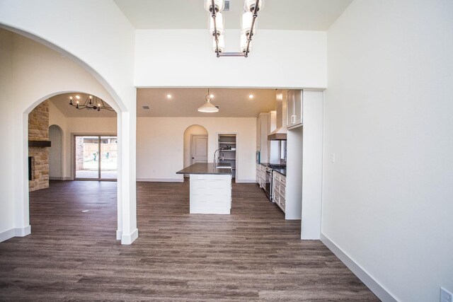 kitchen featuring decorative light fixtures, white cabinets, dark hardwood / wood-style flooring, a notable chandelier, and a center island with sink