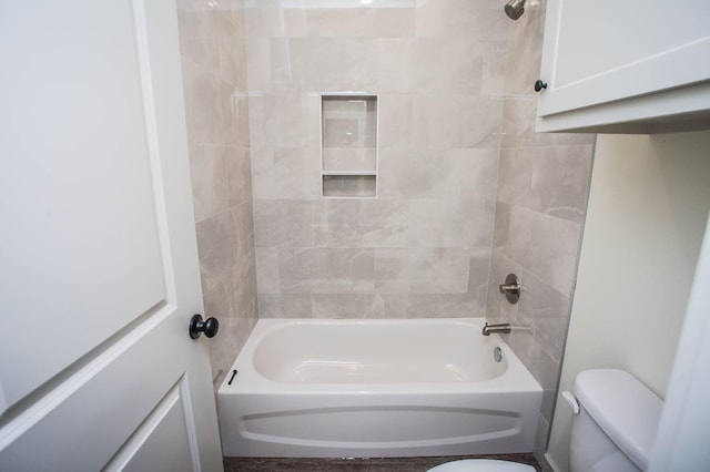 bathroom featuring tiled shower / bath combo and toilet