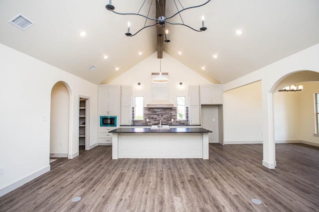 kitchen featuring white cabinetry, built in microwave, a kitchen island with sink, and premium range hood