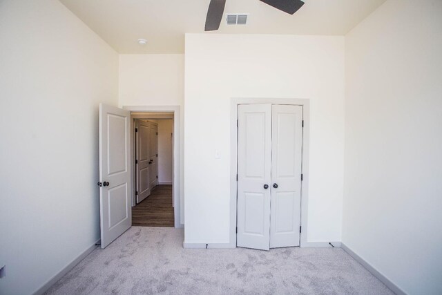 unfurnished bedroom featuring ceiling fan, a closet, and light carpet