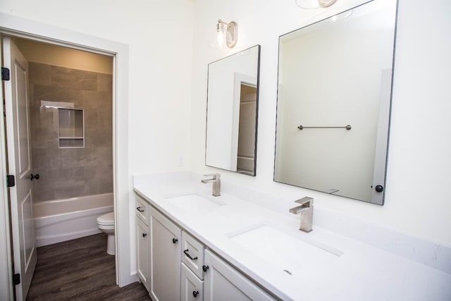 full bathroom featuring vanity, toilet, tiled shower / bath combo, and hardwood / wood-style floors