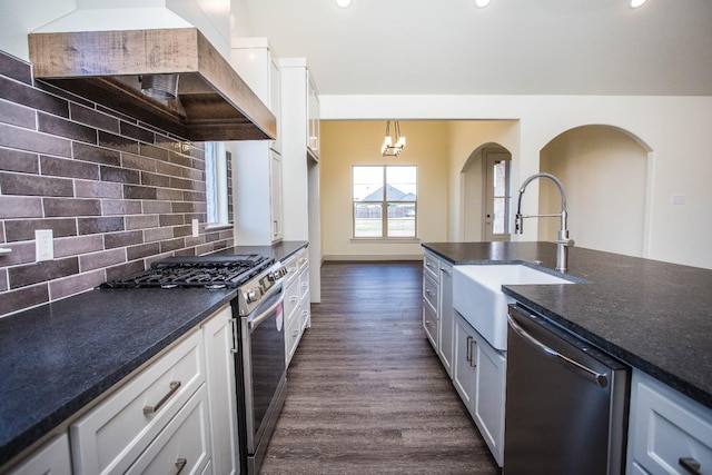 kitchen with white cabinetry, backsplash, dark stone countertops, stainless steel appliances, and custom range hood