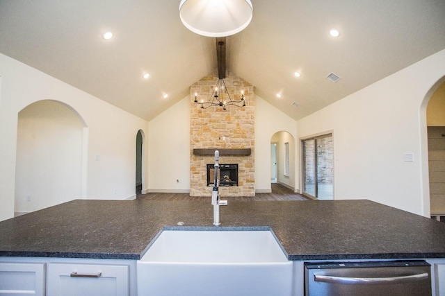 kitchen featuring sink, dishwasher, a fireplace, white cabinets, and beamed ceiling