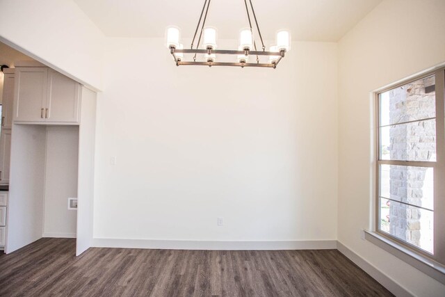 unfurnished dining area with dark wood-type flooring and a chandelier