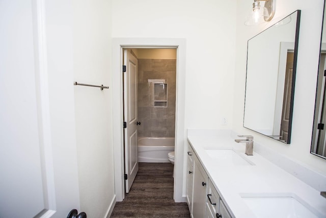 full bathroom with tiled shower / bath combo, vanity, hardwood / wood-style flooring, and toilet