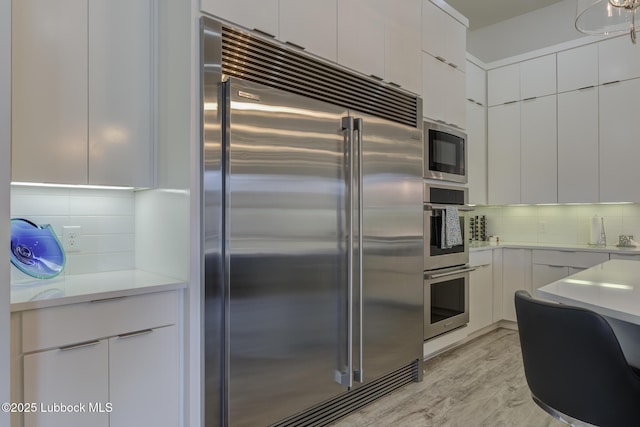 11604 Uxbridge Ave, Lubbock, TX 79424 - kitchen featuring built in appliances, backsplash, white cabinetry, and light countertops