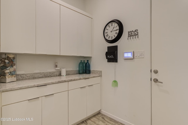 11604 Uxbridge Ave, Lubbock, TX 79424 - kitchen with white cabinetry, light wood-style flooring, and light stone countertops