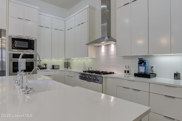11604 Uxbridge Ave, Lubbock, TX 79424 - kitchen featuring wall chimney range hood, appliances with stainless steel finishes, modern cabinets, and light countertops