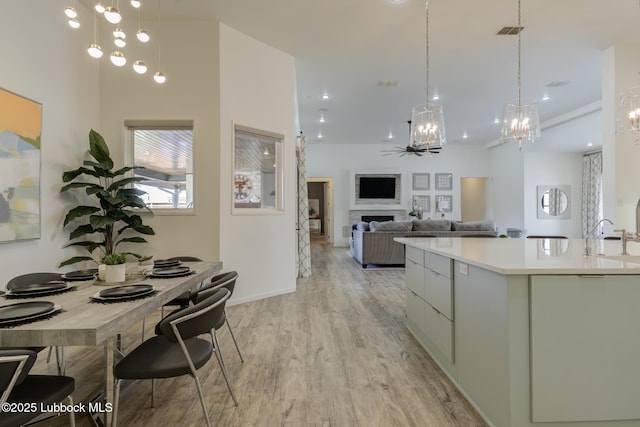 11604 Uxbridge Ave, Lubbock, TX 79424 - kitchen with a chandelier, light wood-style flooring, light countertops, a fireplace, and decorative light fixtures