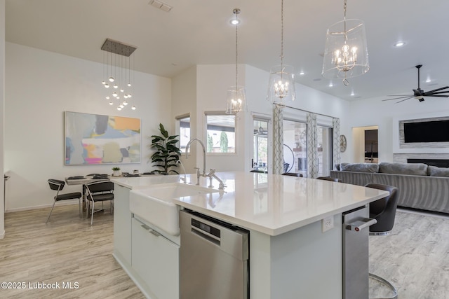 11604 Uxbridge Ave, Lubbock, TX 79424 - kitchen featuring stainless steel dishwasher, open floor plan, a kitchen island with sink, light wood finished floors, and recessed lighting