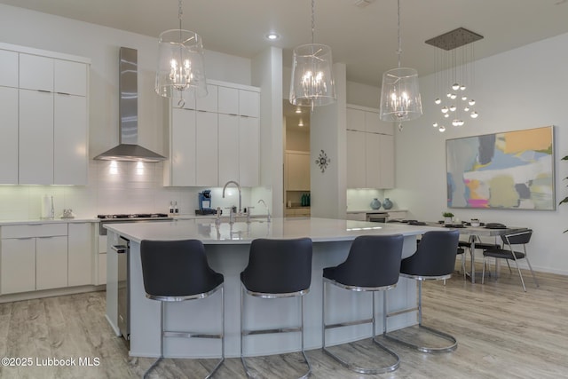 11604 Uxbridge Ave, Lubbock, TX 79424 - kitchen with wall chimney range hood, modern cabinets, light wood-style floors, and tasteful backsplash