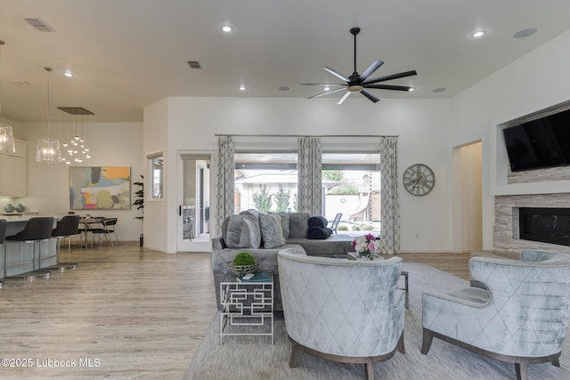 11604 Uxbridge Ave, Lubbock, TX 79424 - living room featuring light wood-style floors, a chandelier, ceiling fan, a stone fireplace, and recessed lighting