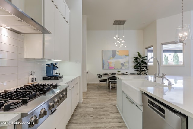 11604 Uxbridge Ave, Lubbock, TX 79424 - kitchen featuring under cabinet range hood, stainless steel appliances, light wood finished floors, and decorative light fixtures