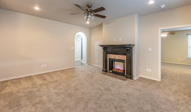 unfurnished living room featuring ceiling fan, light colored carpet, and a premium fireplace