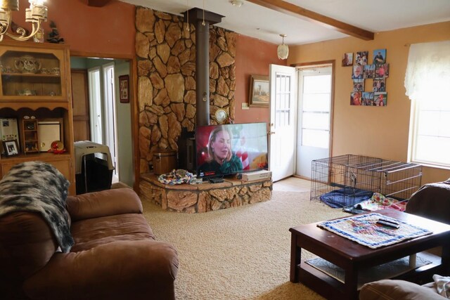 carpeted living room featuring beamed ceiling and a wood stove