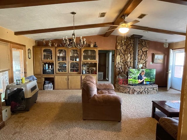 carpeted living room featuring lofted ceiling with beams, a wood stove, ceiling fan with notable chandelier, and a textured ceiling