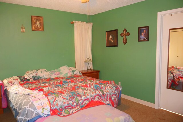 bedroom with ceiling fan, carpet, and a textured ceiling