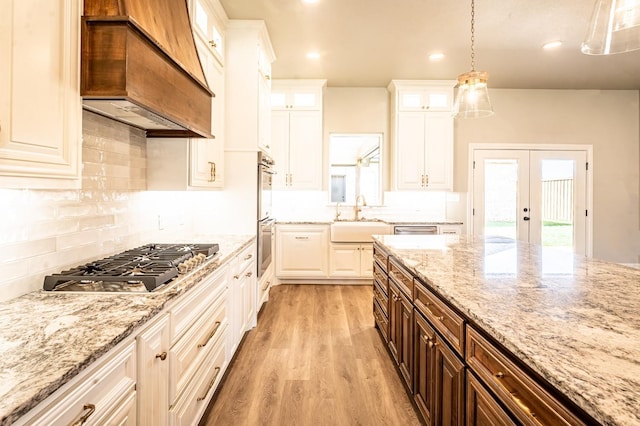 kitchen featuring decorative light fixtures, sink, white cabinets, custom exhaust hood, and stainless steel appliances