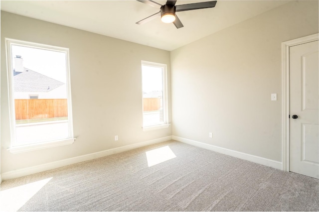 carpeted spare room featuring a wealth of natural light and ceiling fan