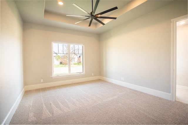 carpeted spare room featuring ceiling fan and a tray ceiling