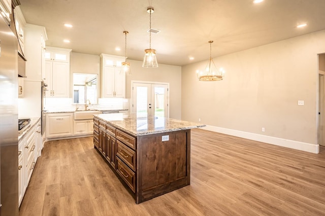 kitchen featuring french doors, dark brown cabinetry, white cabinetry, a center island, and hanging light fixtures