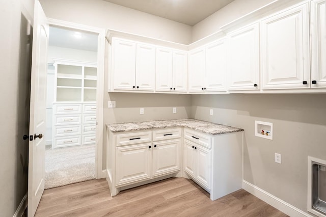 laundry area with hookup for a washing machine, light hardwood / wood-style flooring, and cabinets