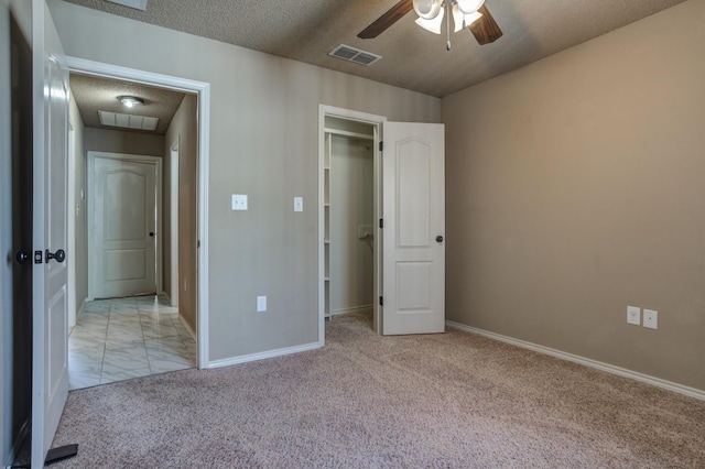 unfurnished bedroom with a closet, ceiling fan, light colored carpet, and a textured ceiling