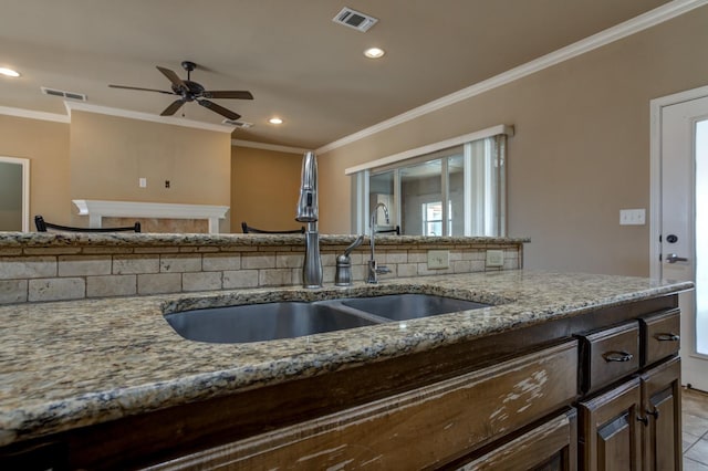 kitchen featuring light tile patterned flooring, sink, ornamental molding, ceiling fan, and light stone counters