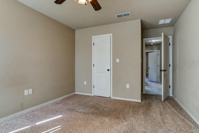 unfurnished bedroom with light colored carpet, a textured ceiling, and ceiling fan