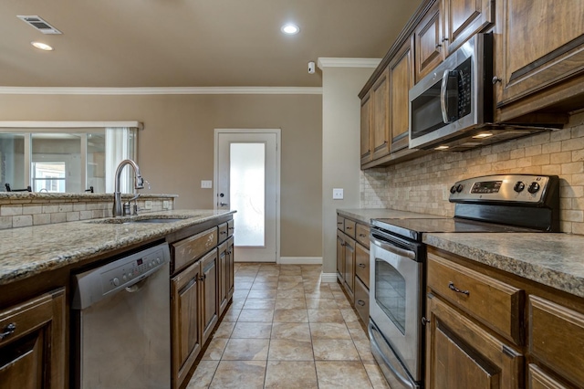 kitchen with sink, crown molding, light tile patterned floors, appliances with stainless steel finishes, and decorative backsplash