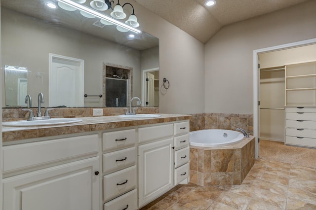 bathroom featuring plus walk in shower, vaulted ceiling, vanity, and a textured ceiling