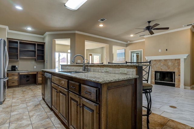 kitchen with sink, light tile patterned floors, a kitchen breakfast bar, an island with sink, and stainless steel appliances