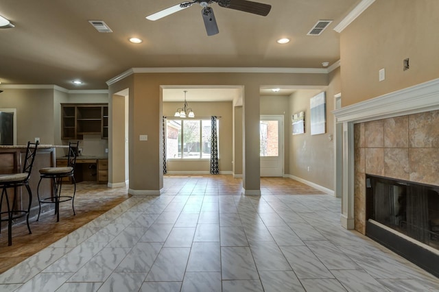 living room with a tiled fireplace, ceiling fan with notable chandelier, and ornamental molding