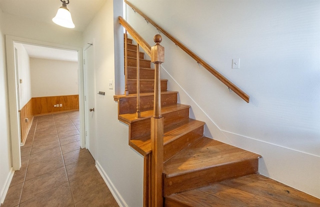 stairs with tile patterned flooring and wooden walls