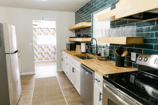 kitchen featuring butcher block counters, sink, white cabinets, decorative backsplash, and stainless steel appliances