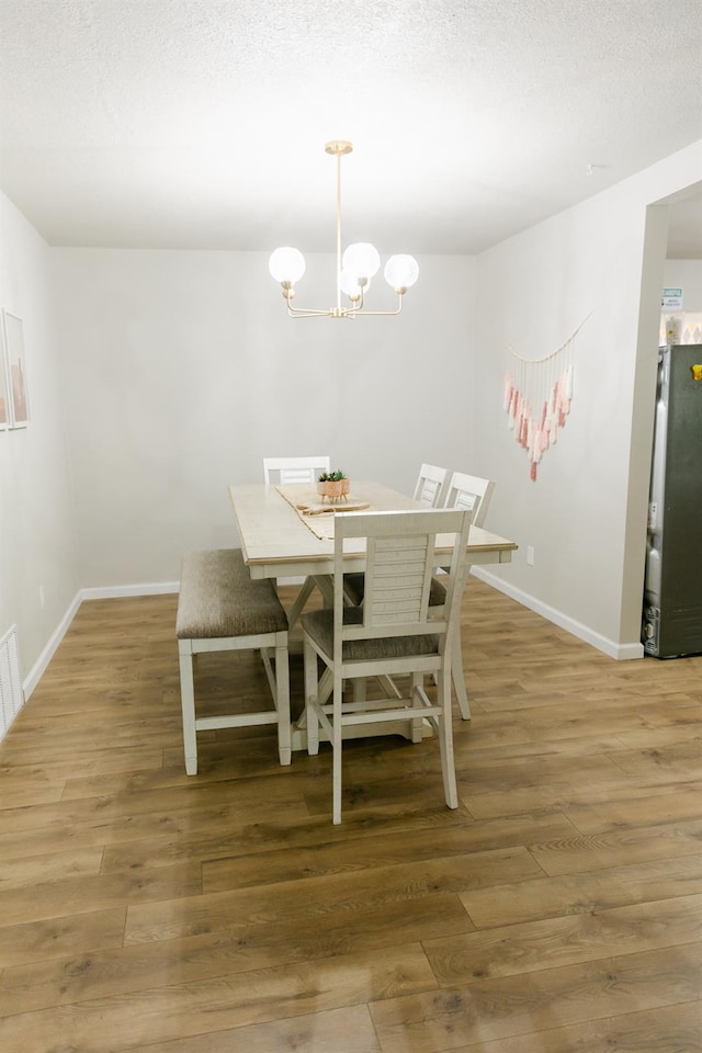 dining area featuring dark hardwood / wood-style floors, a notable chandelier, and a textured ceiling