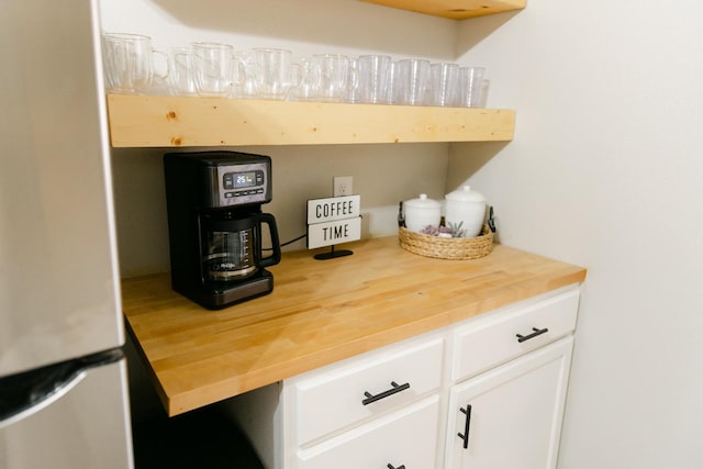 interior space with white cabinetry, wood counters, and stainless steel refrigerator