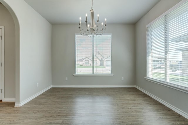 spare room with hardwood / wood-style flooring and a notable chandelier