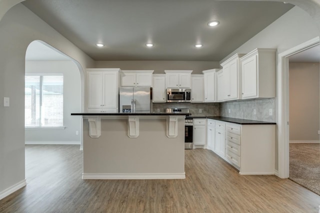 kitchen with white cabinetry, stainless steel appliances, a center island, and a breakfast bar area