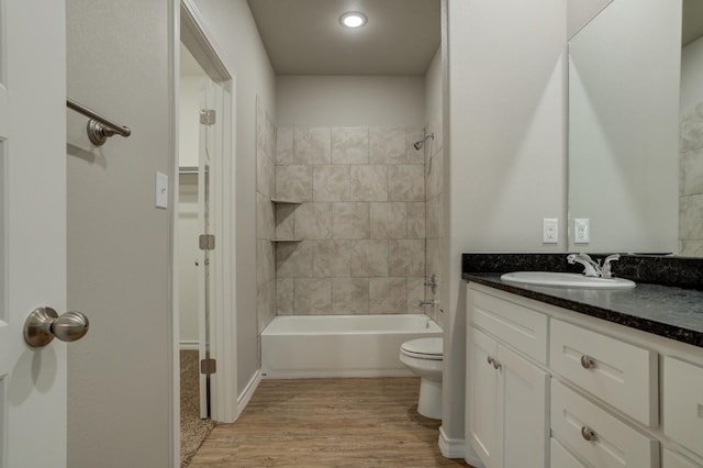 full bathroom with hardwood / wood-style flooring, vanity, toilet, and tiled shower / bath combo