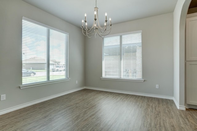 spare room featuring a chandelier and hardwood / wood-style floors