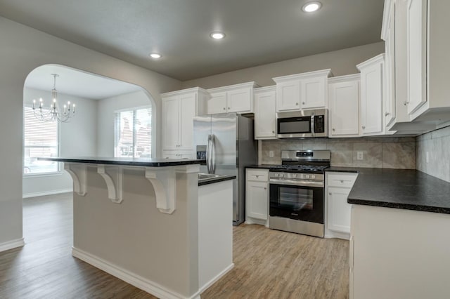 kitchen with pendant lighting, stainless steel appliances, a center island, and white cabinets