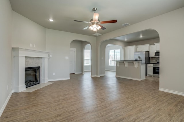 unfurnished living room featuring ceiling fan, a fireplace, and light wood-type flooring