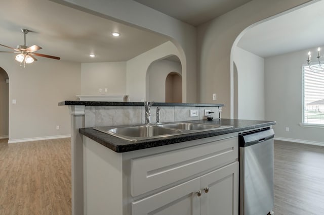 kitchen with white cabinetry, an island with sink, sink, stainless steel dishwasher, and light hardwood / wood-style flooring