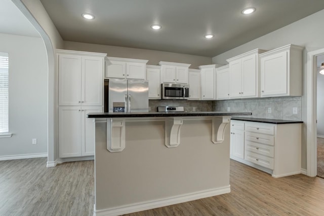 kitchen featuring stainless steel appliances, a center island, light hardwood / wood-style flooring, and white cabinets