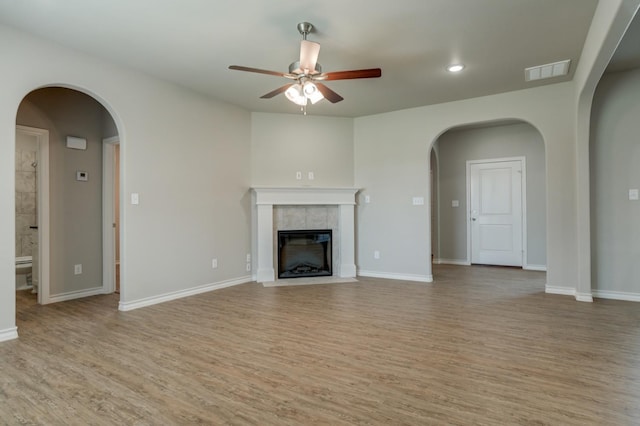 unfurnished living room featuring light hardwood / wood-style flooring, a tile fireplace, and ceiling fan