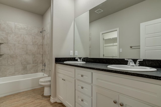 full bathroom with vanity, wood-type flooring, toilet, and tiled shower / bath