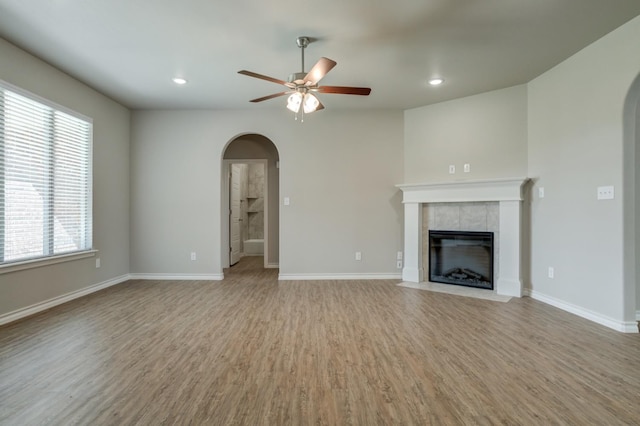 unfurnished living room with a tile fireplace, hardwood / wood-style floors, and ceiling fan