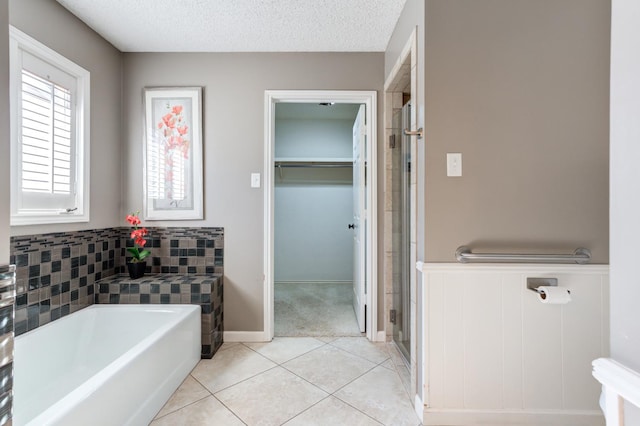 bathroom featuring tile patterned flooring, independent shower and bath, and a textured ceiling